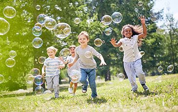 image of children playing in a park with bubbles