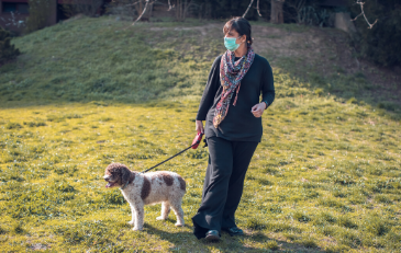 Photo of woman with face covering walking a dog